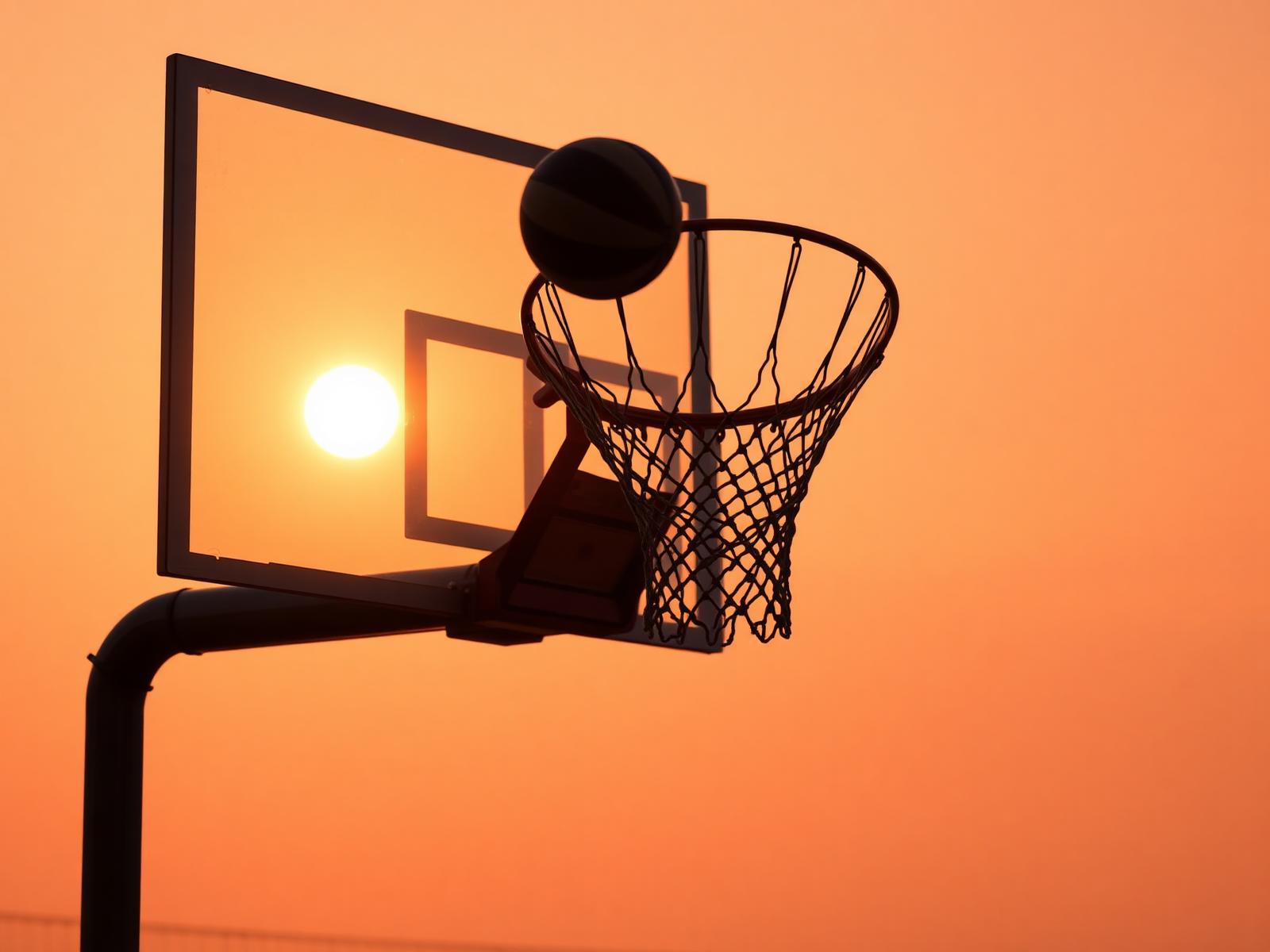 Basketball swishing through hoop at sunset